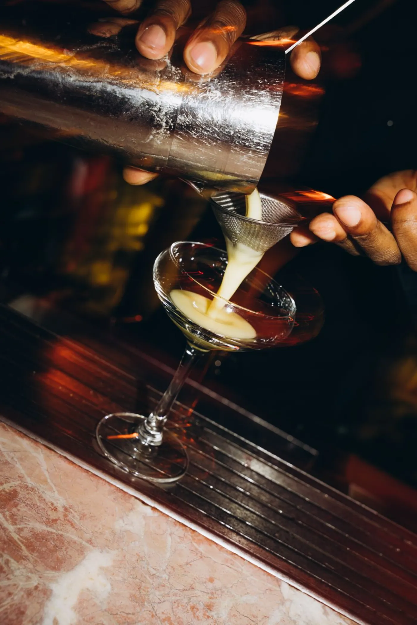 Cocktail being strained into a coupe at the bar