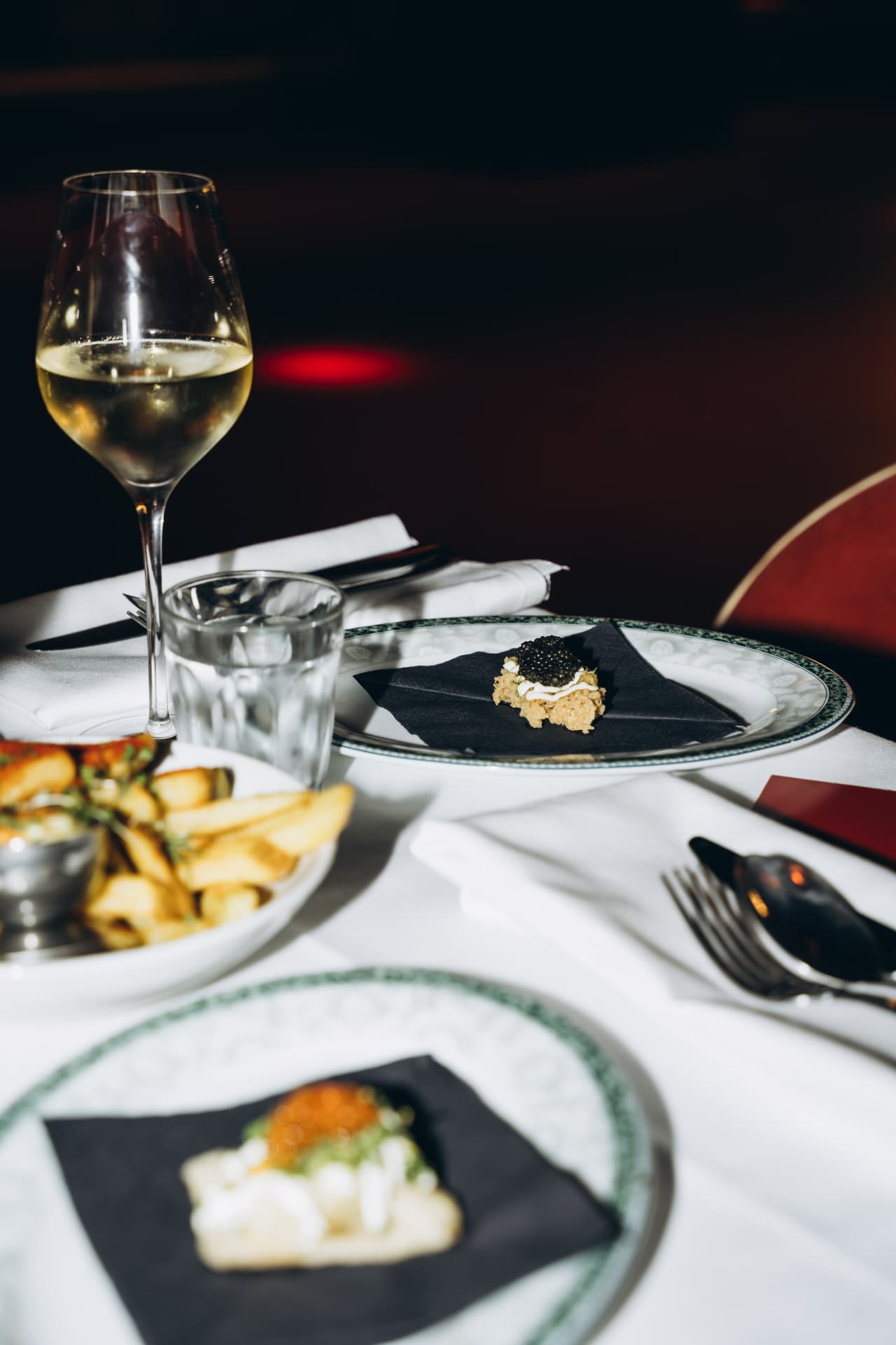 Caviar bite with a glass of white wine on white table linen